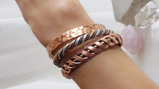 womens wrist with three different copper bracelets
