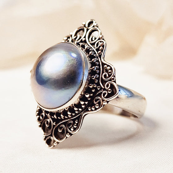 zijkant closeup van zilveren ring met blauwe parel