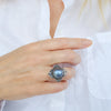 hand met closeup van zilveren ring met blauwe parel