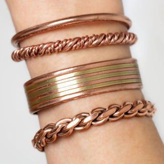 vier koperen armbanden om een pols